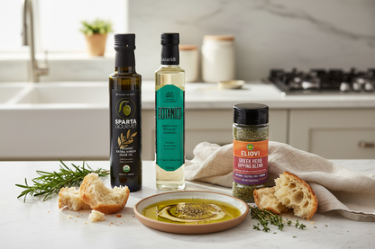 Mediterranean bread dipping set with Sparta Gourmet Organic olive oil, Botanico White Balsamic, and Eliovi herb blend on rustic linen with crusty bread, oregano, and lemon